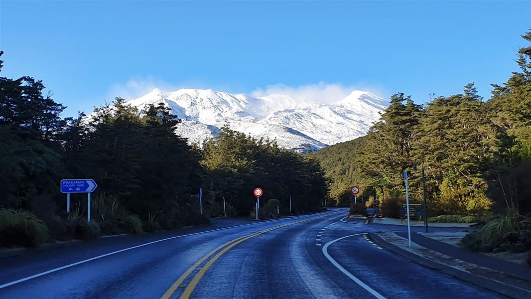 A view of a large snowy topped mountain from the road.