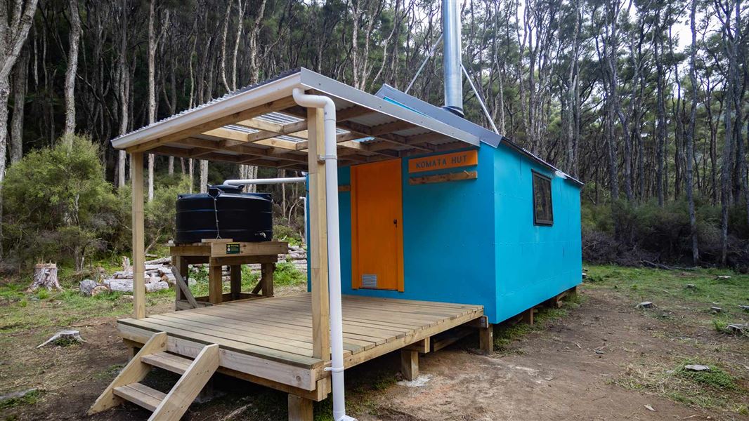 Bright blue hut with orange door and balcony. 