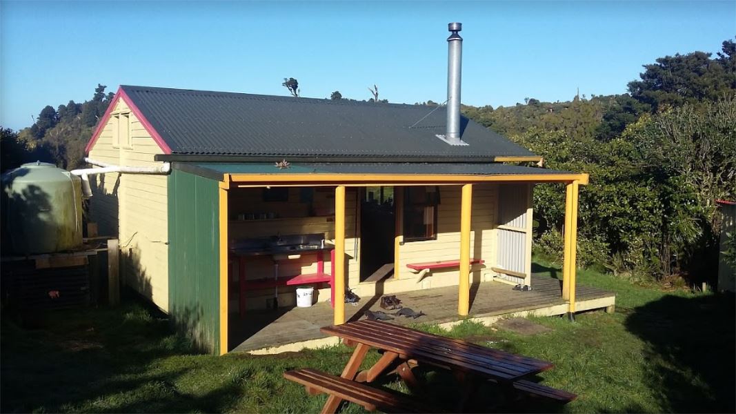 A green hut with yellow columns, shown on a sunny day.