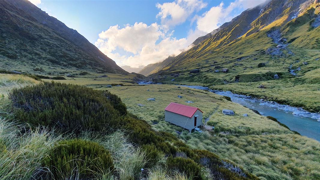 Small building by river and hills.