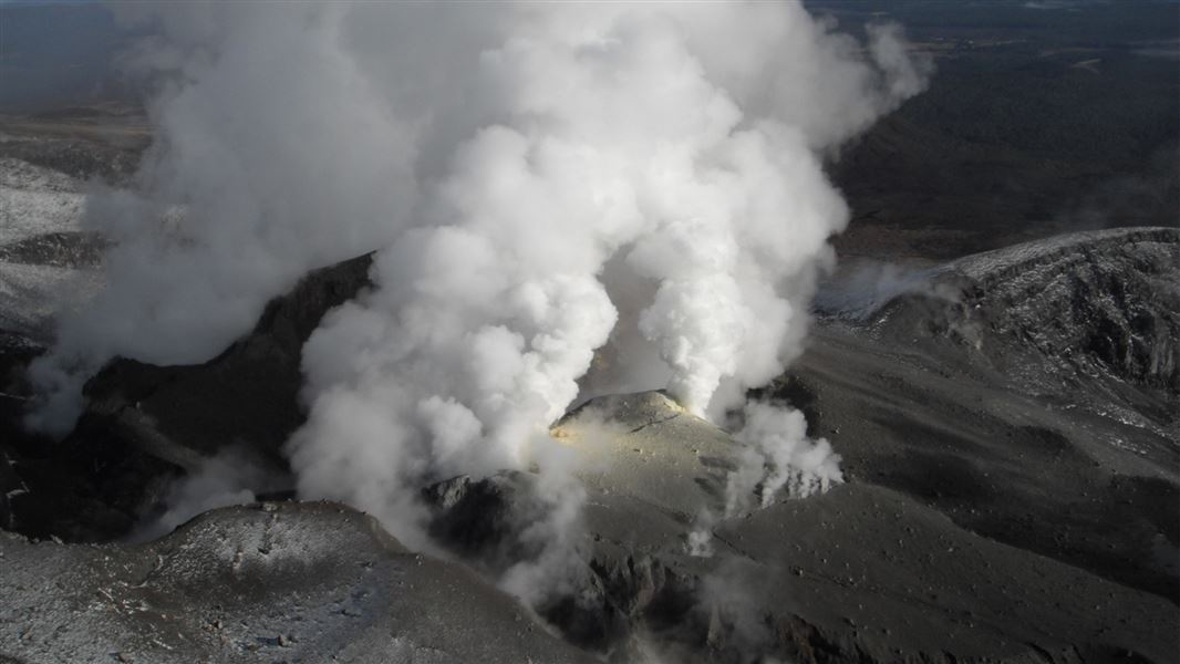 Photo of Mount Tongariro upper vents emit volcanic smoke.