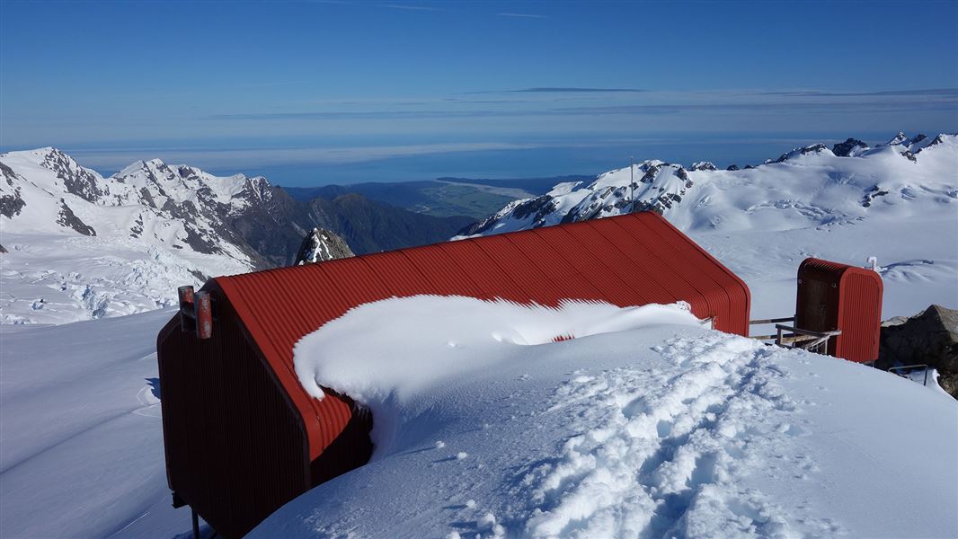 Small red building partially covered by snow.