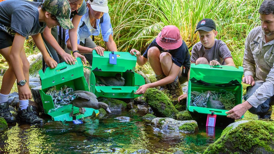 Happy children release whio into the wild.