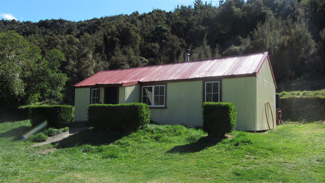 Small building on grass with trees nearby.