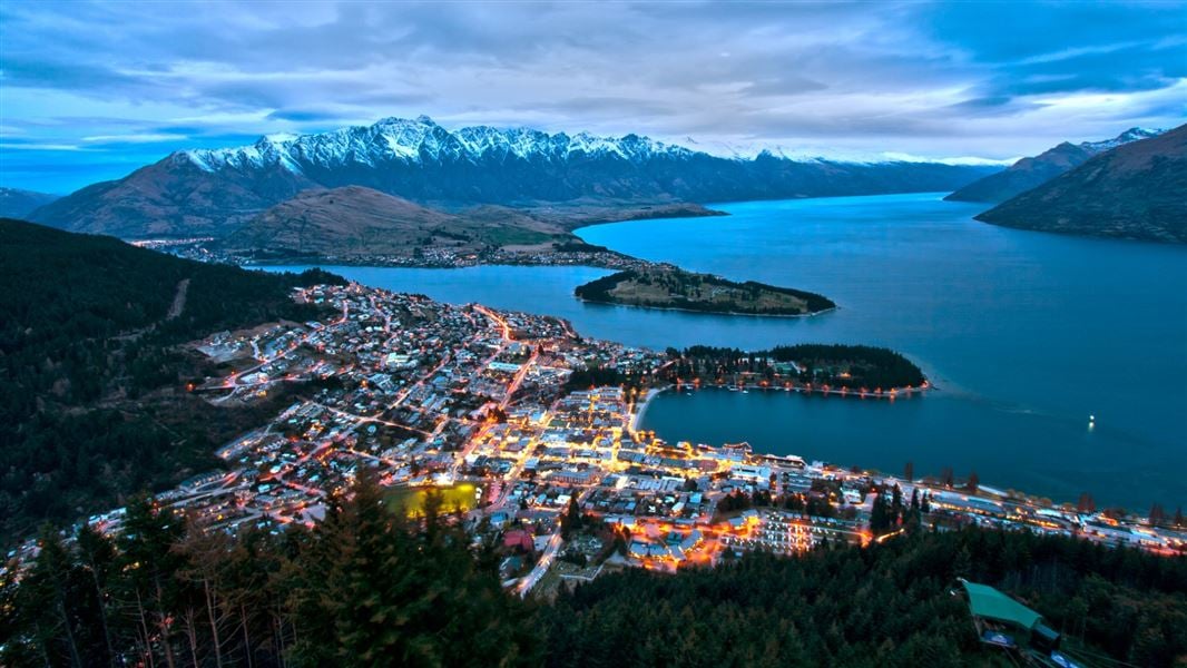 An aerial view of Queenstown, lighting up at dusk.