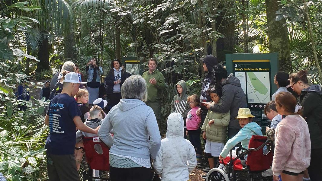 DOC Ranger talking to a group of people including children in the bush.