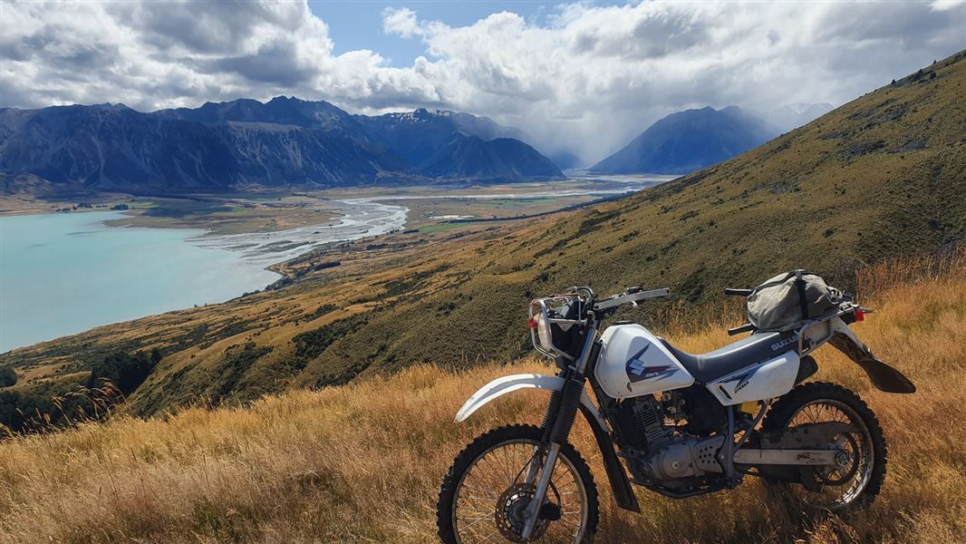 Stream landscape with grassy hills and motorbike in front