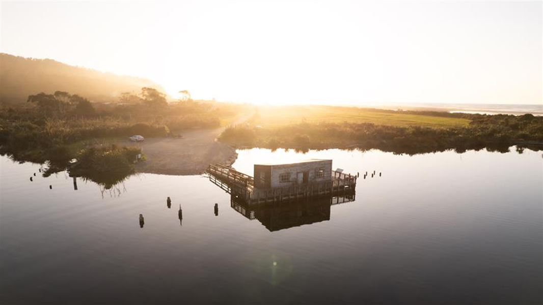 Ōkārito Lagoon boathouse in the sunset.