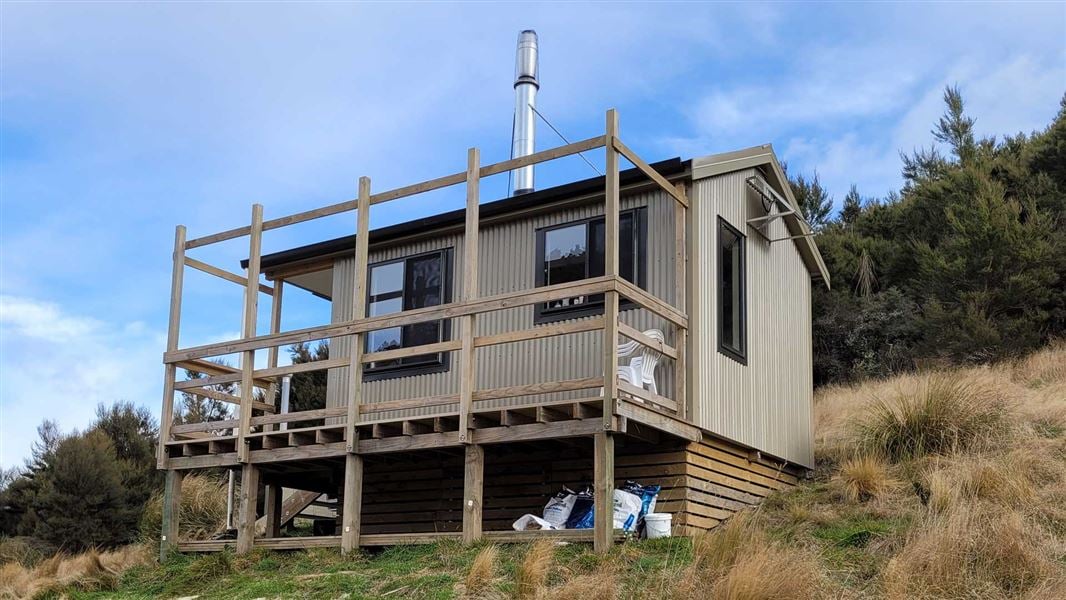 Small hut with balcony on a grassy hillside.