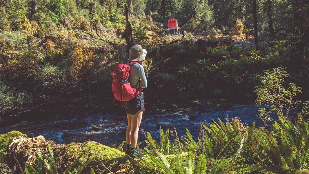 A hiker looks to the other side of a rushing river she has to cross at the Maclennan River