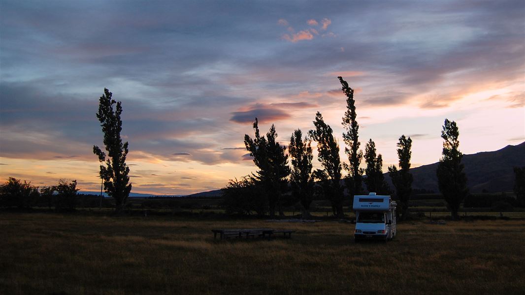 White campervan at grassy campsite.