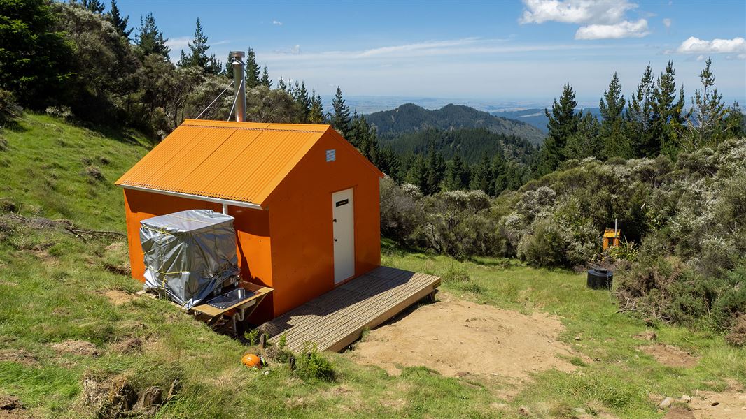 Small orange building on grassy hill.