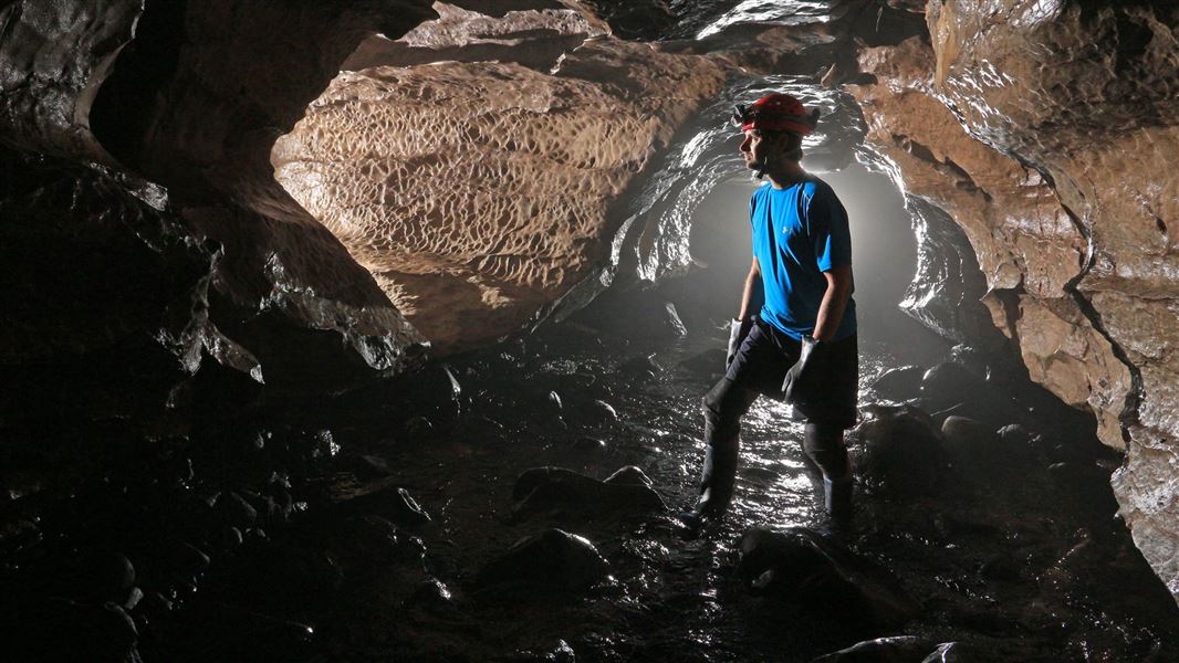 Man admiring Okupata Cave with head torch. 