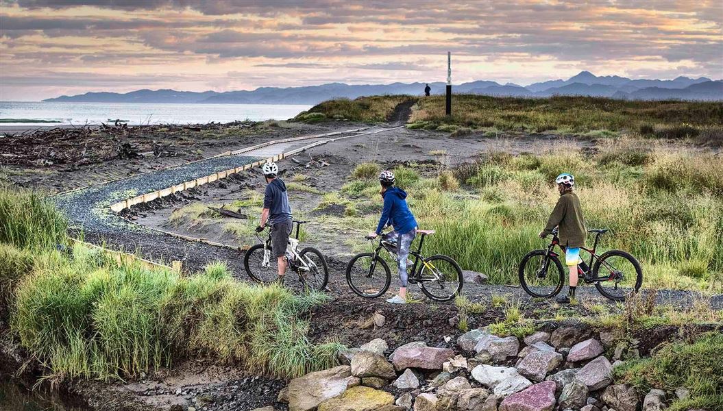 People cycling on dunes with view of beach.