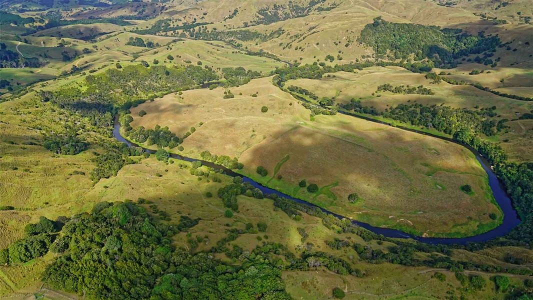 Aerial view of a deep blue river snaking across a rural landscape. Deep green trees dot along the river.