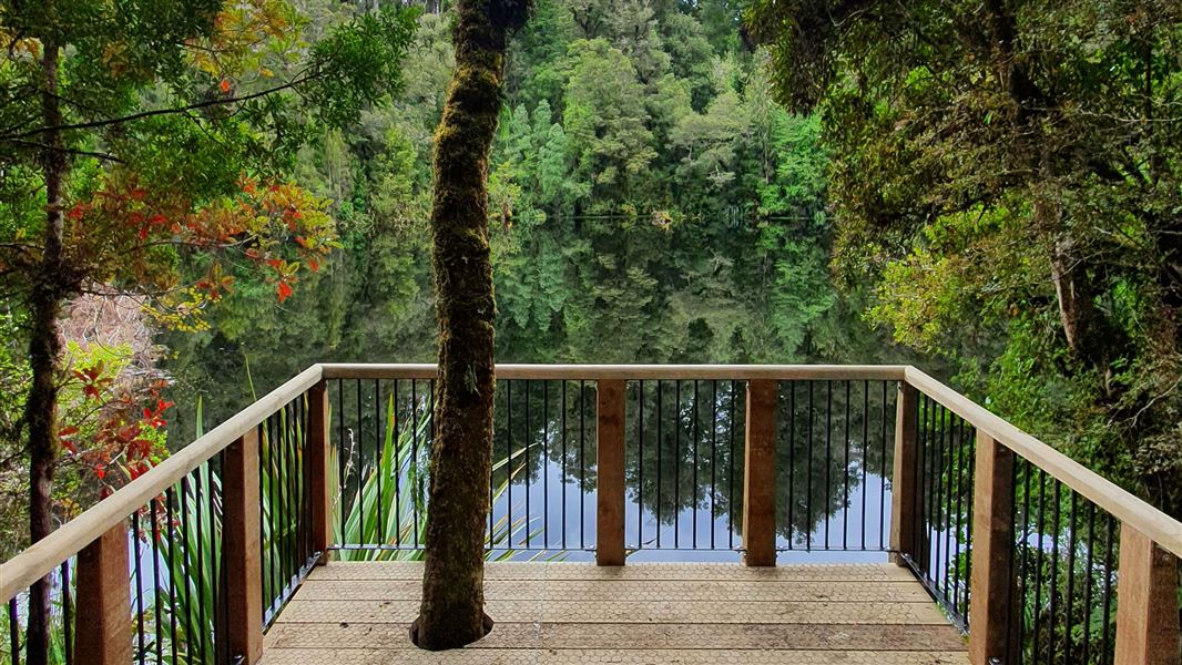 Wooden viewing platform looking over water and trees.