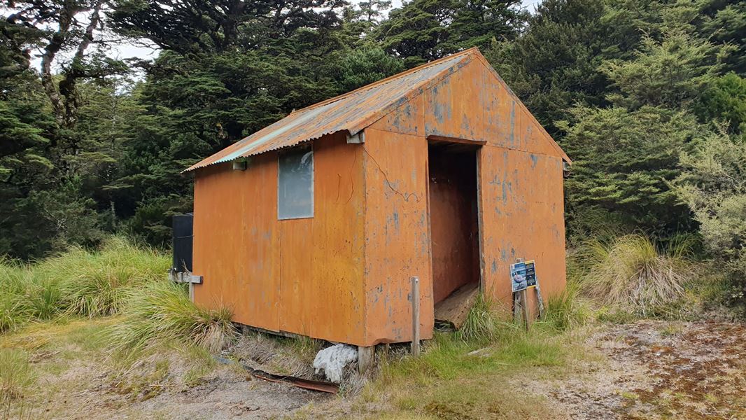 Small orange building by trees.