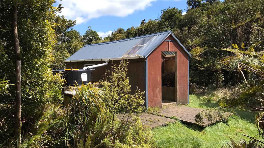 A hut shown surrounded by trees and bush.