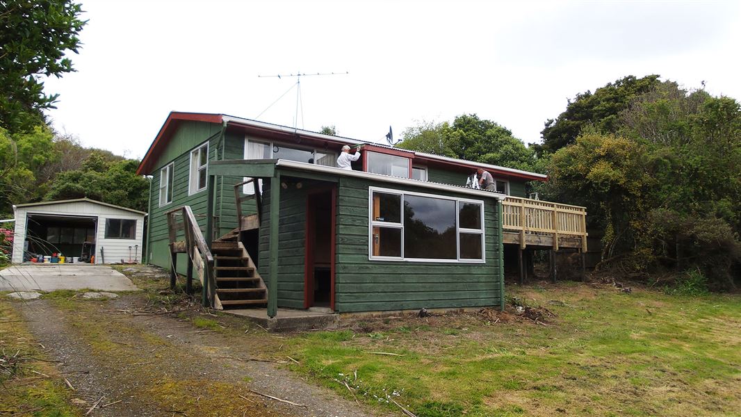 Small wooden building with people doing work.