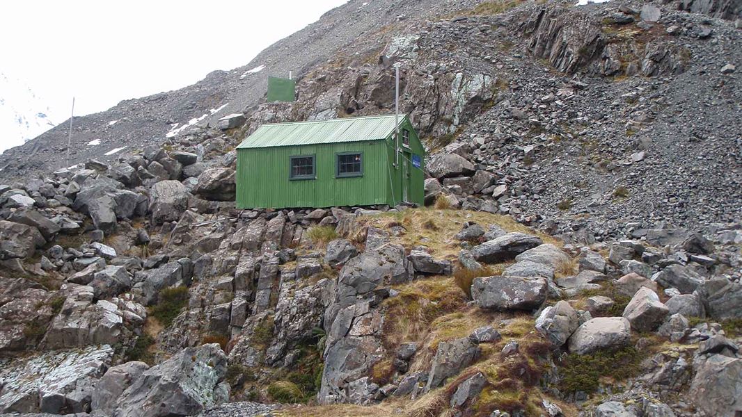 A small green cabin on a rocky outcrop.