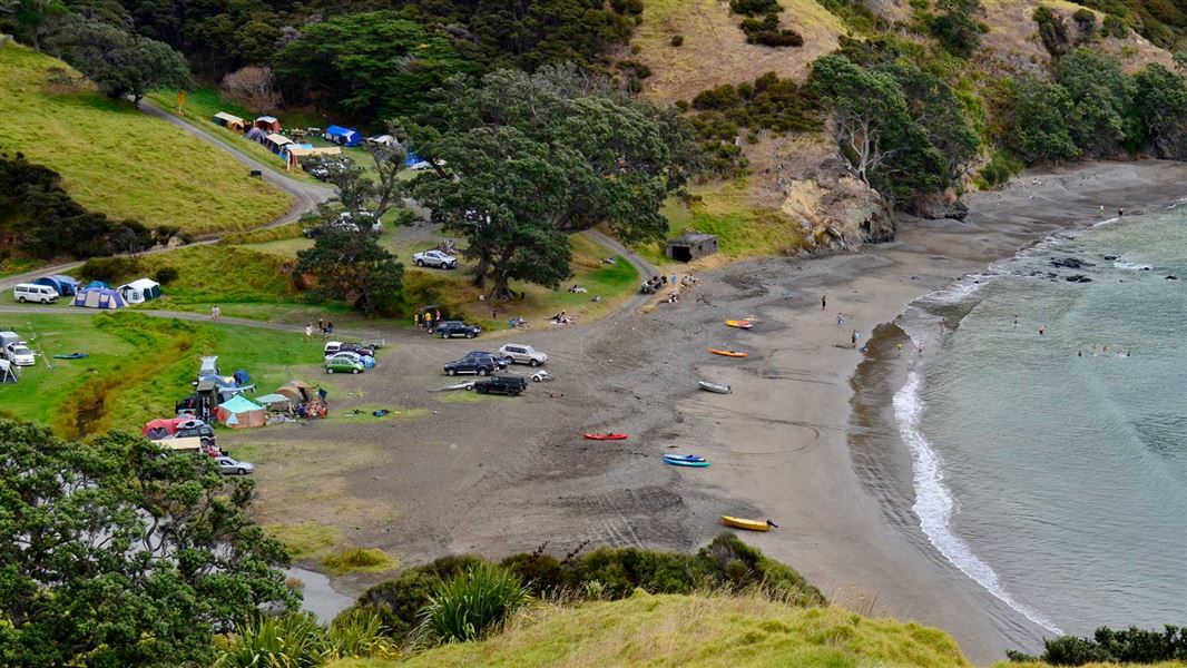 Overlooking a campsite with tents on a green field before a bay.