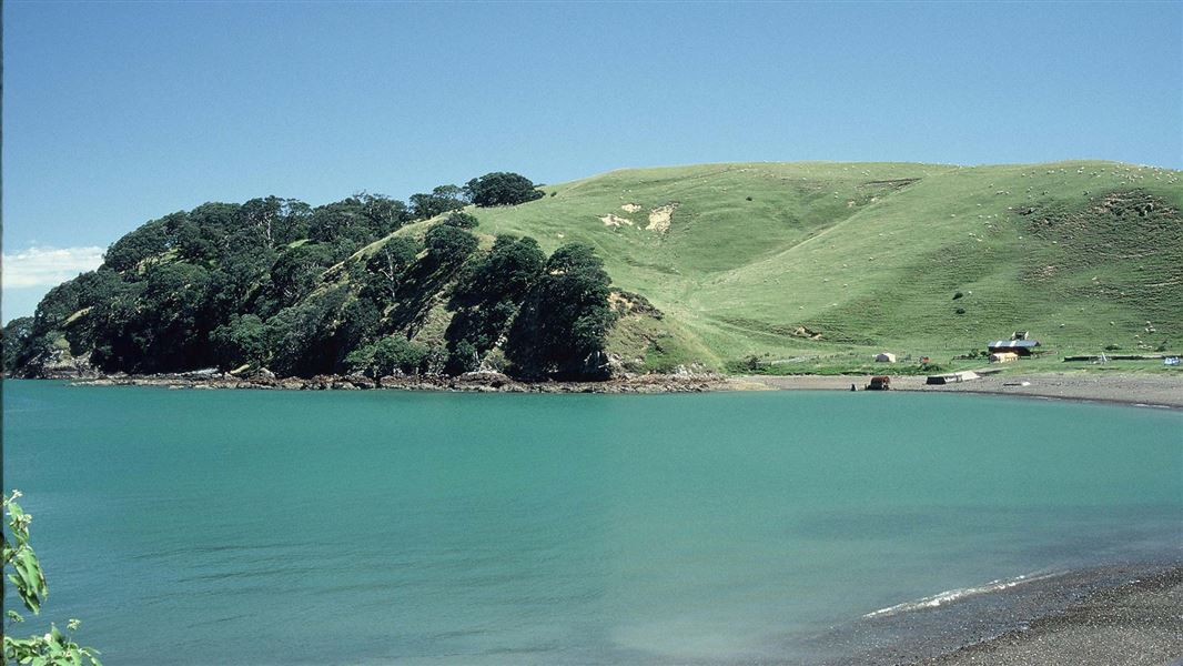 A blue bay with a grassy hill in the background.