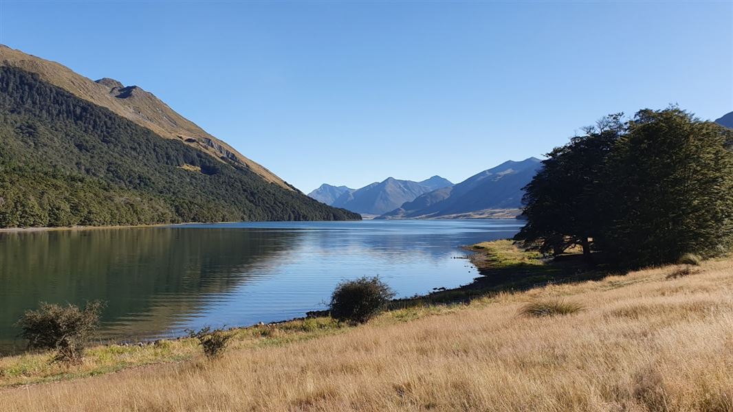 A landscape image of a large lake, surrounded by a mountain range.