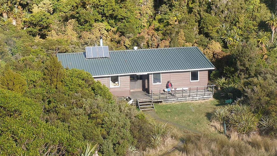 View down onto a large wooden hut. It's surrounded by trees on a hillside.