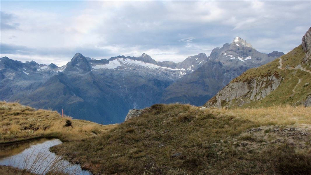 A landscape view of a small lake and distant mountain tops covered in snow.