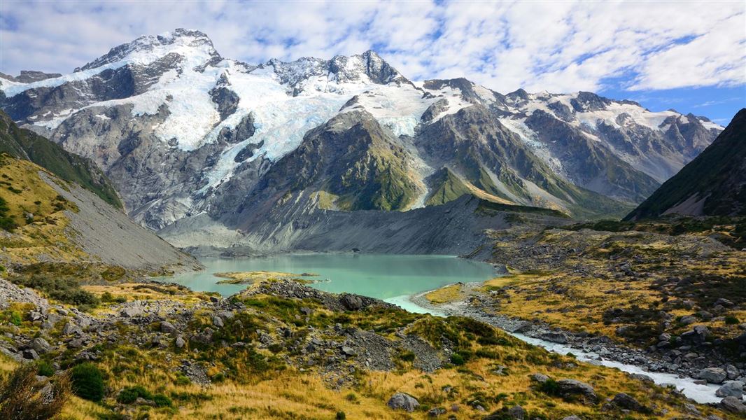 Ice covers mountain peaks with a lake in front of them.