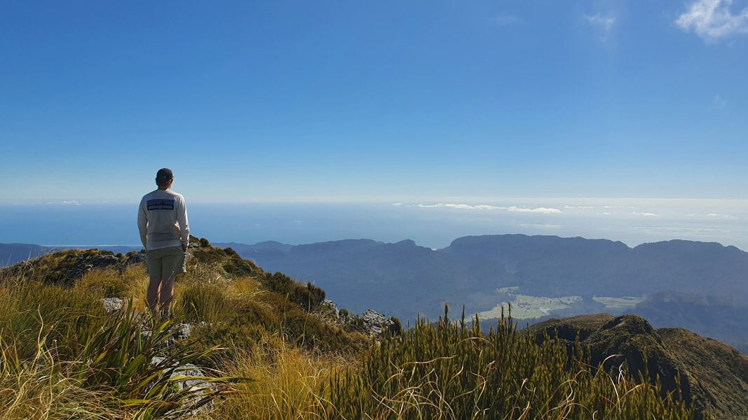 Person standing and looking over mountain tops. 