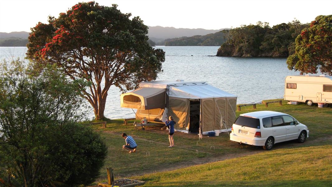 Tent pitched at campsite on seashore with children playing.