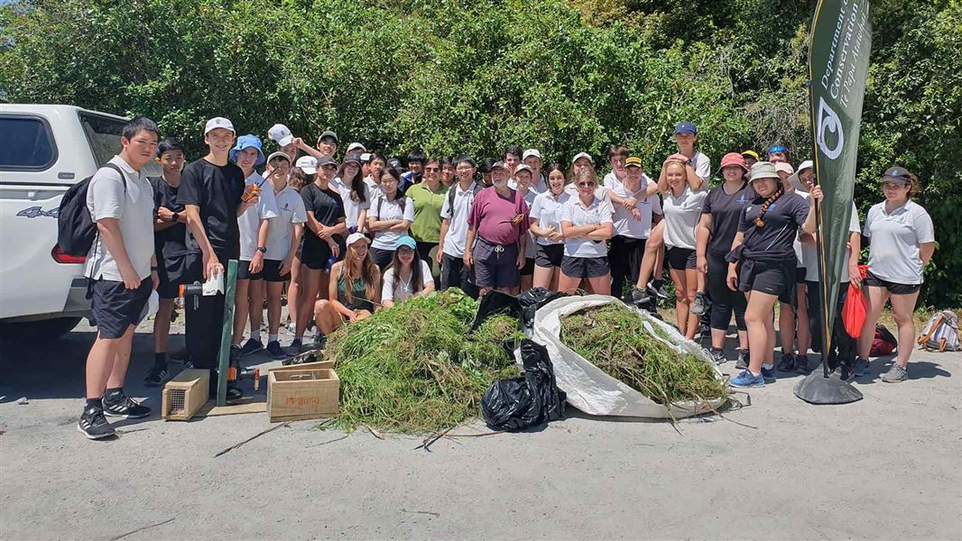 DOC, Friends of Gordon Park and Whanganui Collegiate students with the pile of veldt grass. 