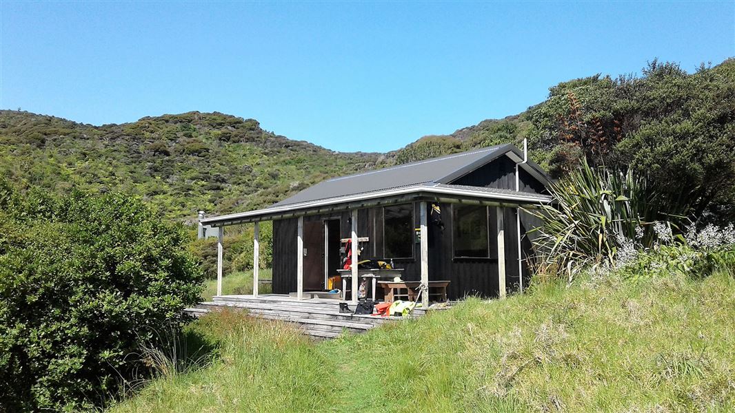 Small building on hill by trees.