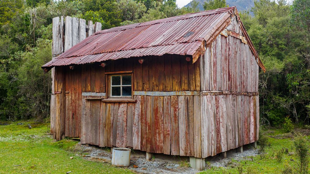 Small wooden building in grassy area.