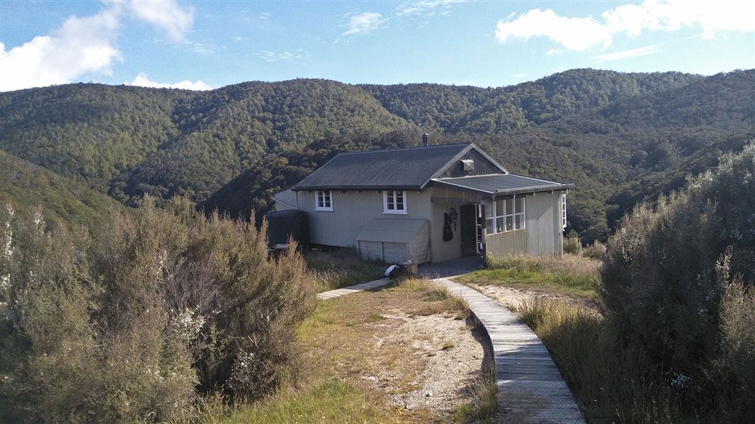 Small building surrounded by tree covered hills.