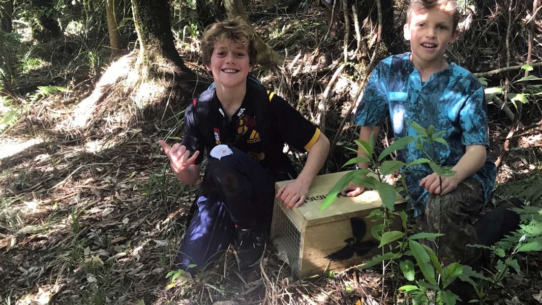 Two children placing a trap in the bush