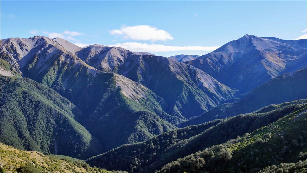 Mountain ranges with scree tips and green vegetation bottoms. 