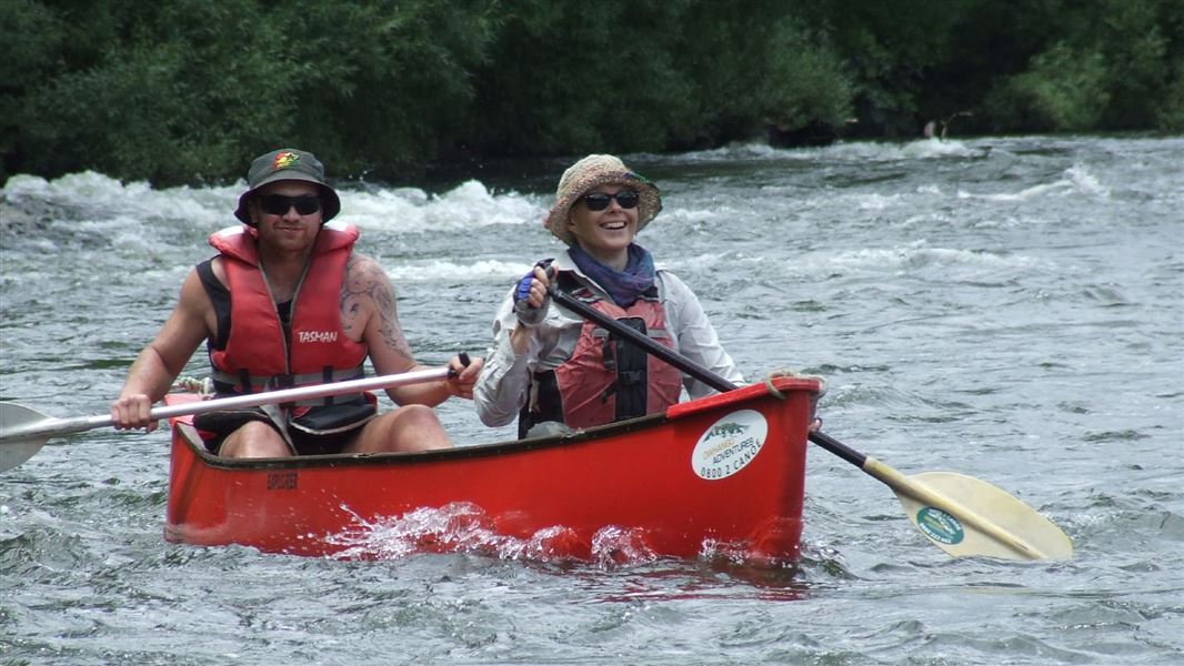 A man and woman in a canoe wearing life jackets