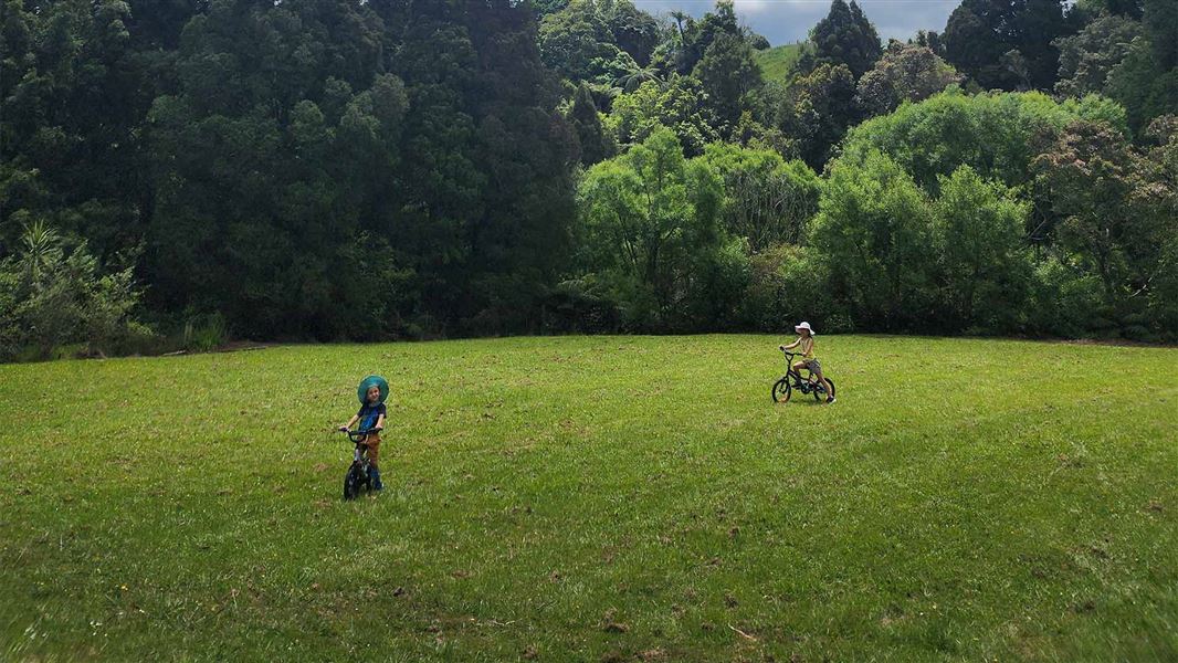 Kaniwhaniwha Campsite two kids riding bikes on grass field