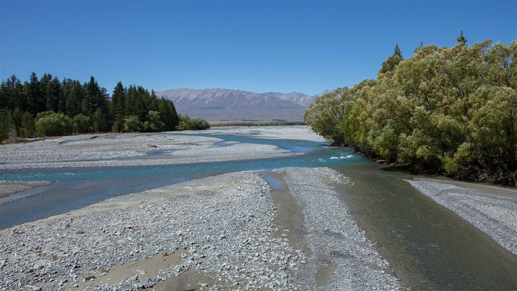 Braided river, stony edge on a blue sky day.