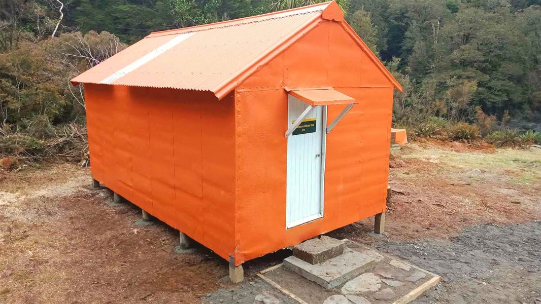 An orange hut surrounded by bush