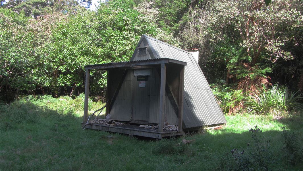 Small triangular building in grassy area.