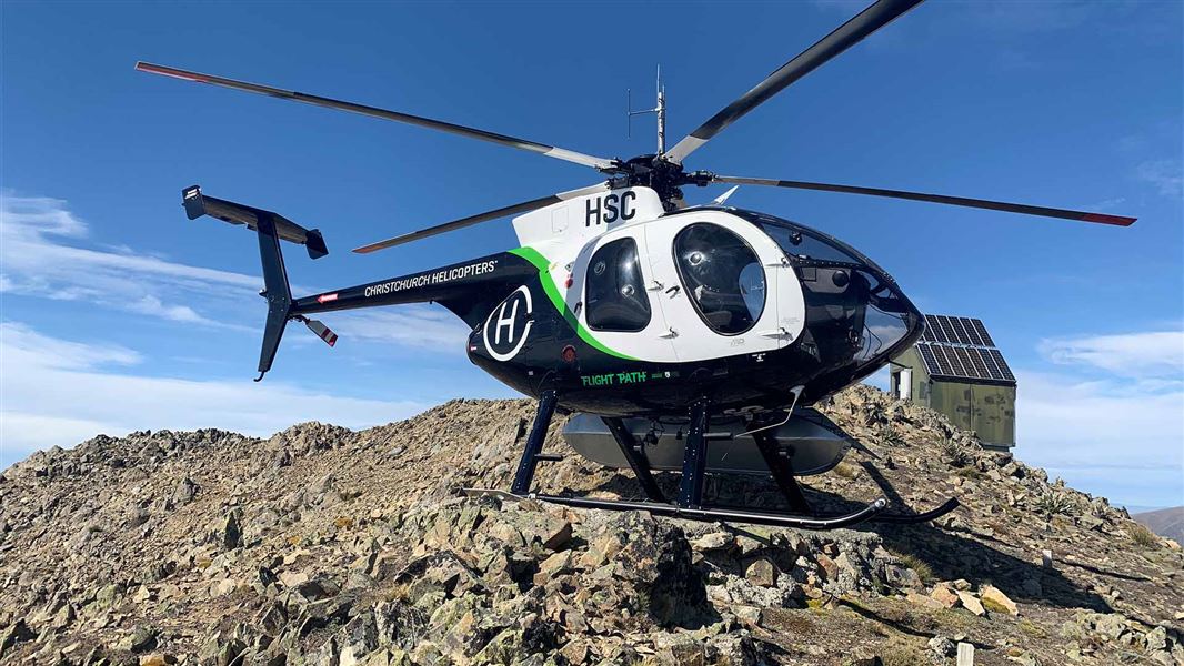 A helicopter with Flight Path branding sits on a mountain