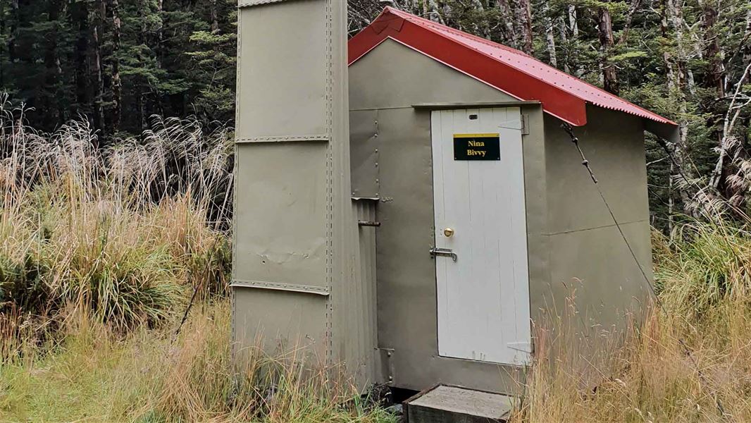 A small sheet metal hut in a small opening in the forest.