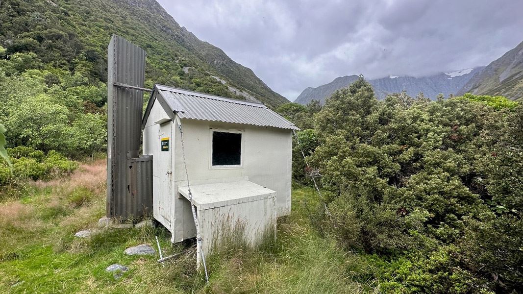 Small hut surrounded by shrubs at high altitude.