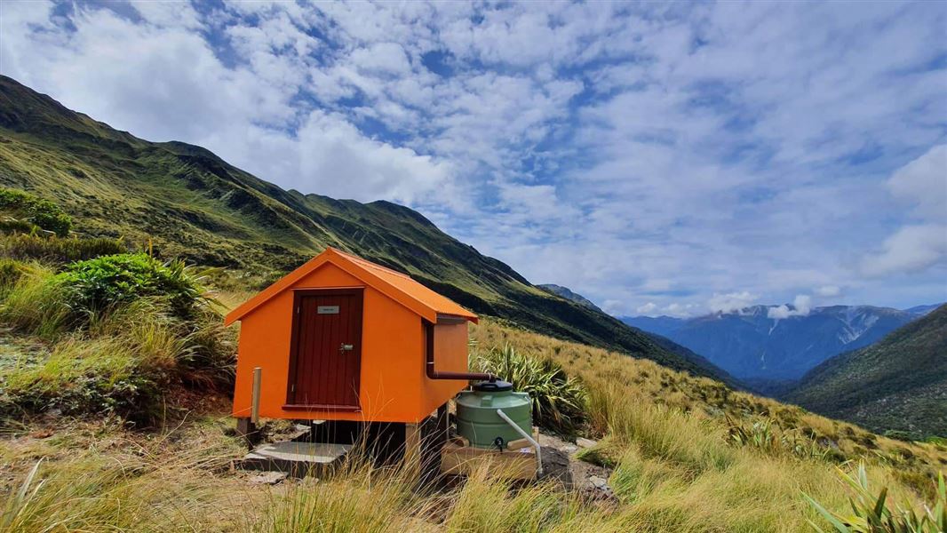 Small orange building on grassy hill.