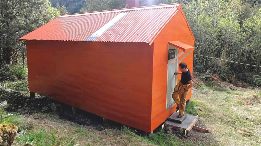 A man leaving a painted orange hut