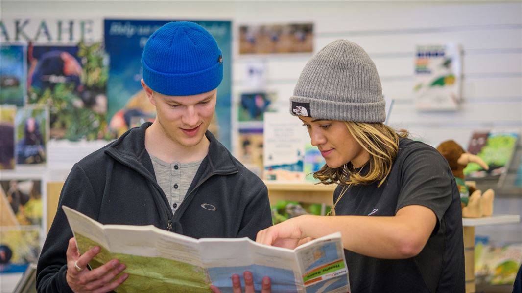 Two people reading a map at a DOC Visitor Centre.