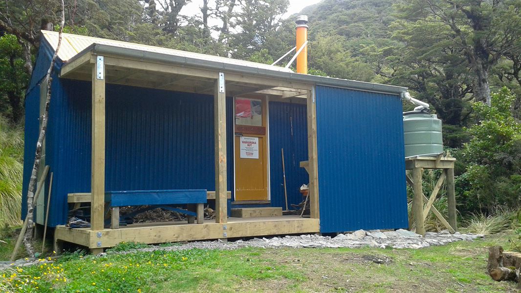 Small blue building surrounded by trees.